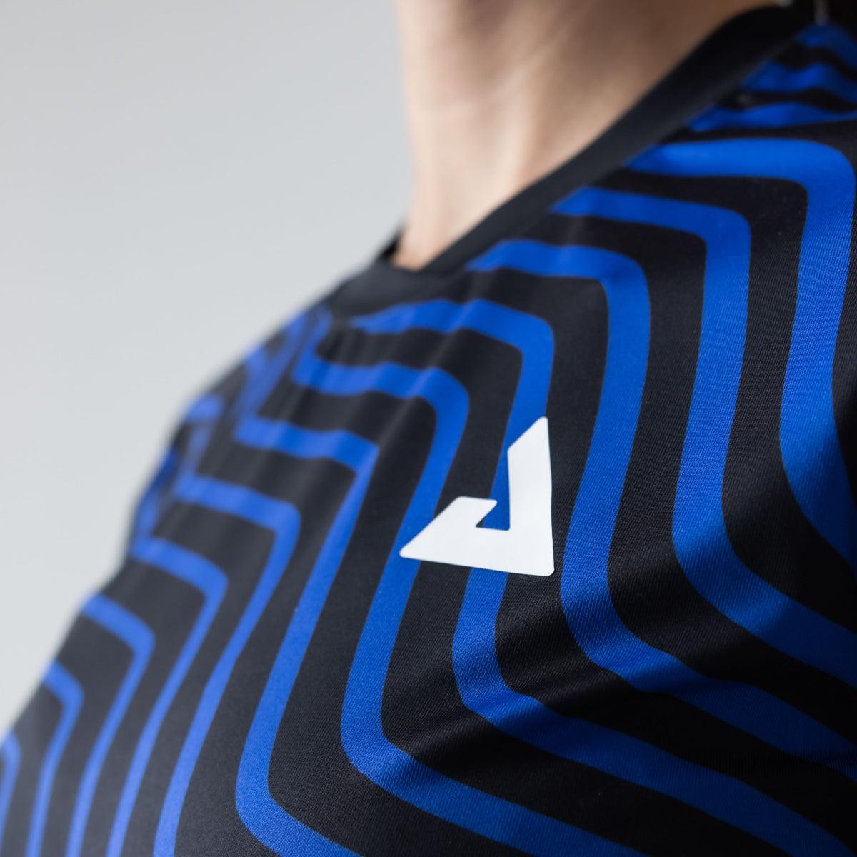 Nahaufnahme eines schwarzen Sportshirts mit blauem Linienmuster und weißem Logo auf der Brust.
