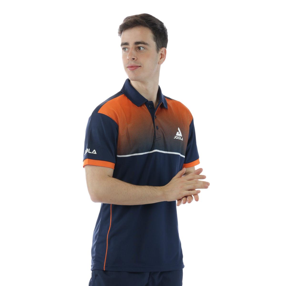 Junger Mann trägt navy-blaues und orangefarbenes Joola-Poloshirt mit kurzem Arm vor weißem Hintergrund.